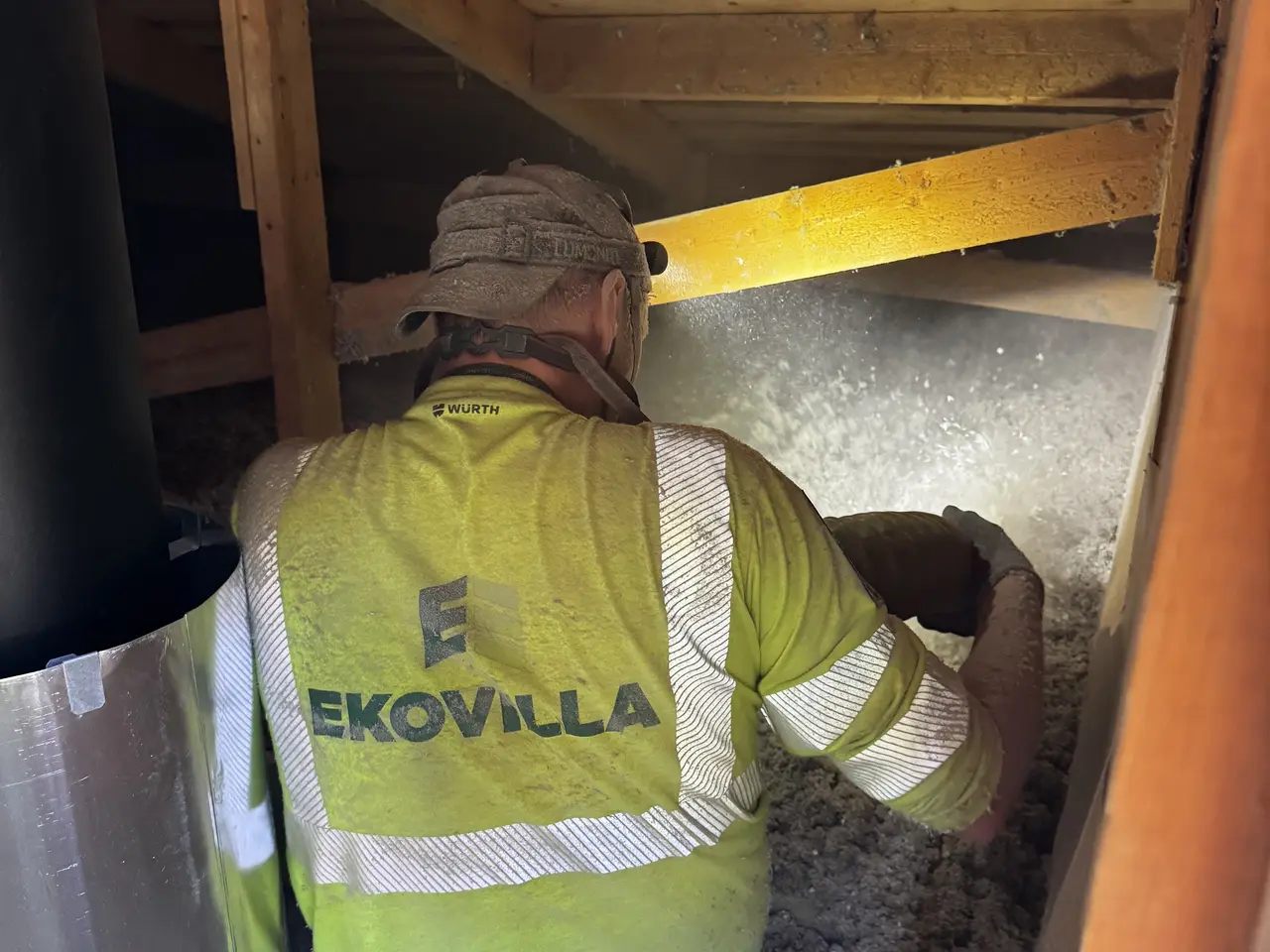 Installatör med lösullsslang vid en vindslucka